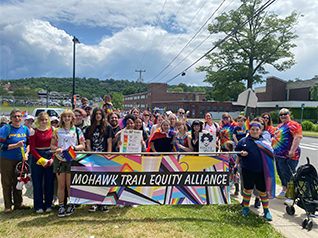 Group of happy students and adults outside holding Mohawk Trail Equity Alliance banner